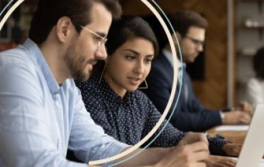 dos personas en el computador con tarjeta en mano