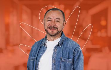 Hombre con chaqueta de jean sonriendo de frente con fondo rojo